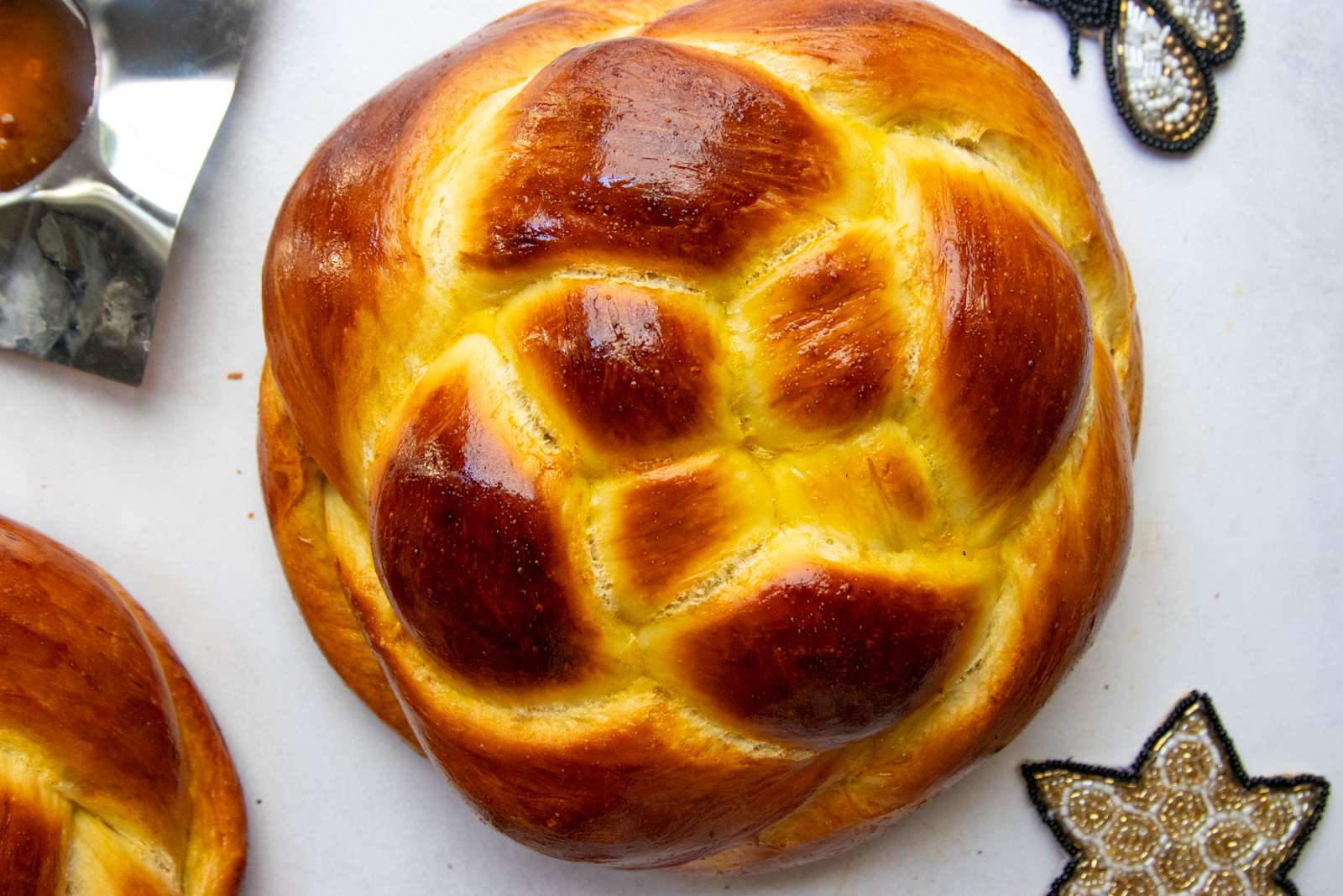 Close-up of a woven round challah with a glossy golden crust