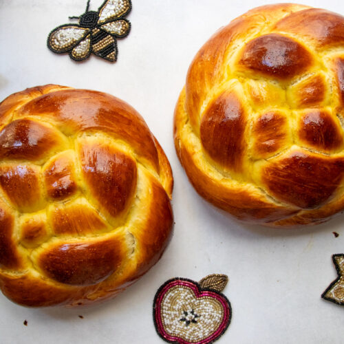 Two woven round challah loaves for Rosh Hashanah with apples and honey