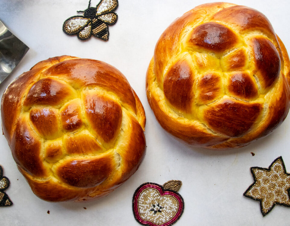 Two woven round challah loaves for Rosh Hashanah with apples and honey