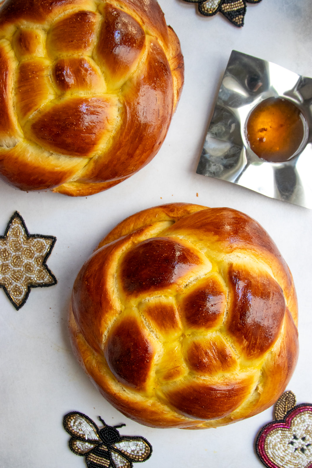 Overhead of round Rosh Hashanah challah with honey and apple decorations