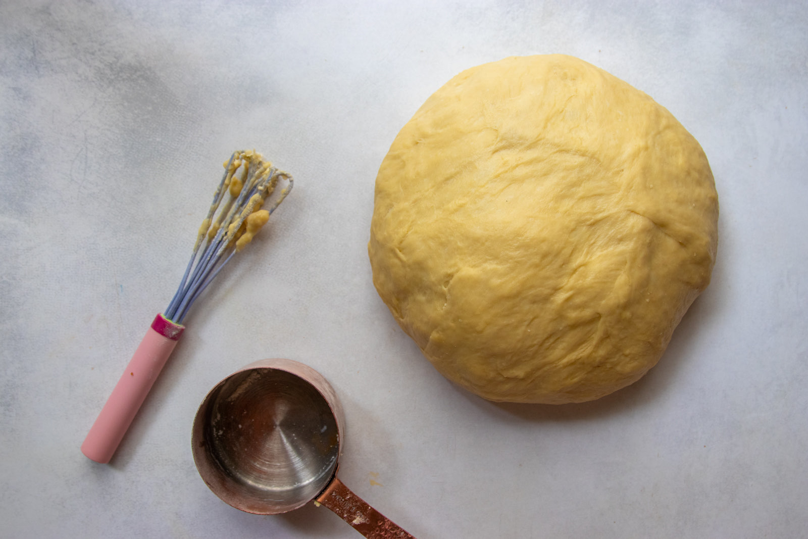 Risen challah dough in a ball ready to be shaped