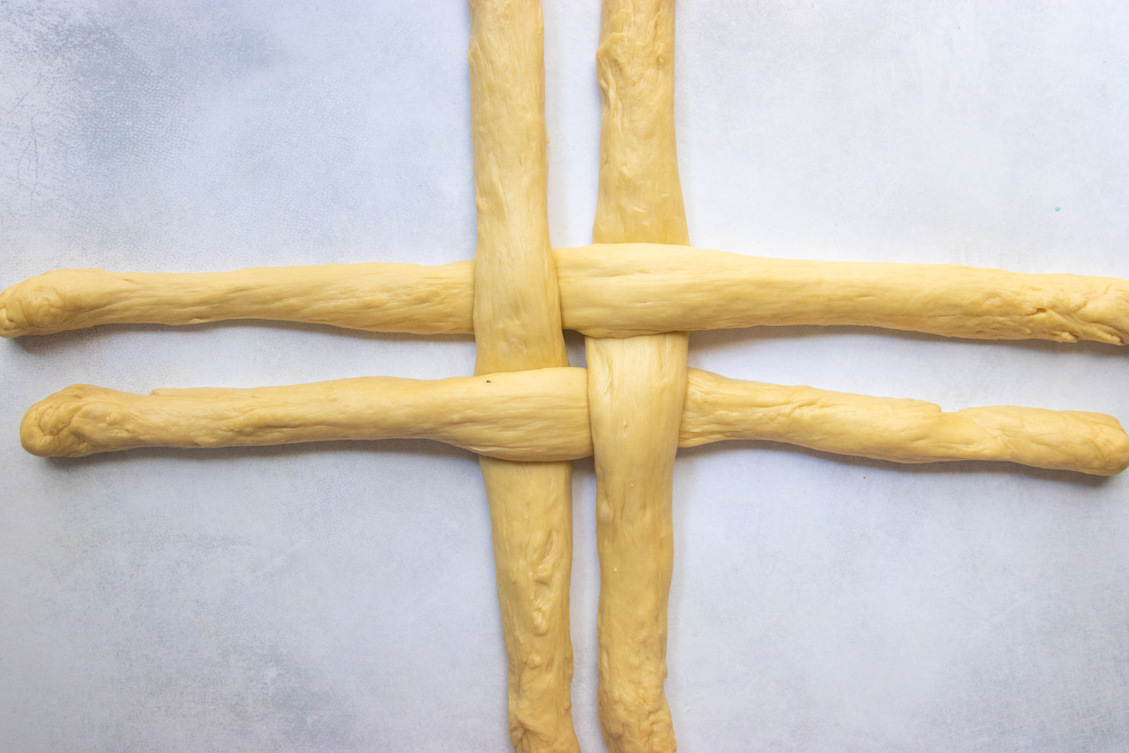 Four challah ropes woven into a tic-tac-toe hashtag shape