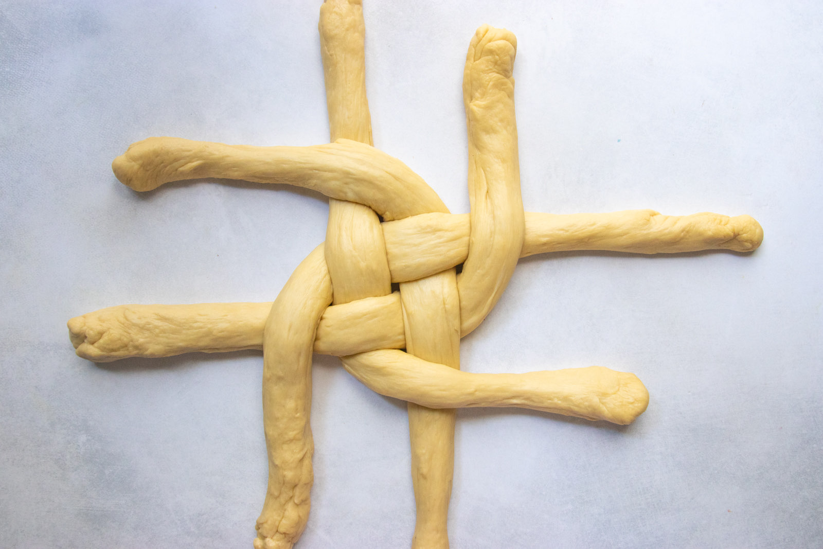 Braiding round challah by crossing the under strand over its neighbor