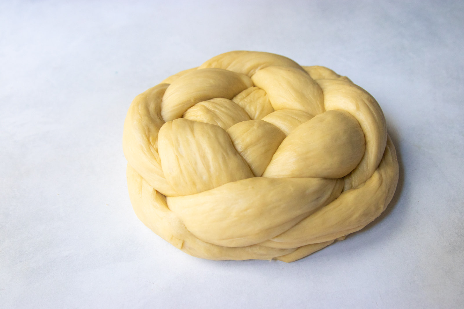 Shaped raw woven round challah resting for its second rise