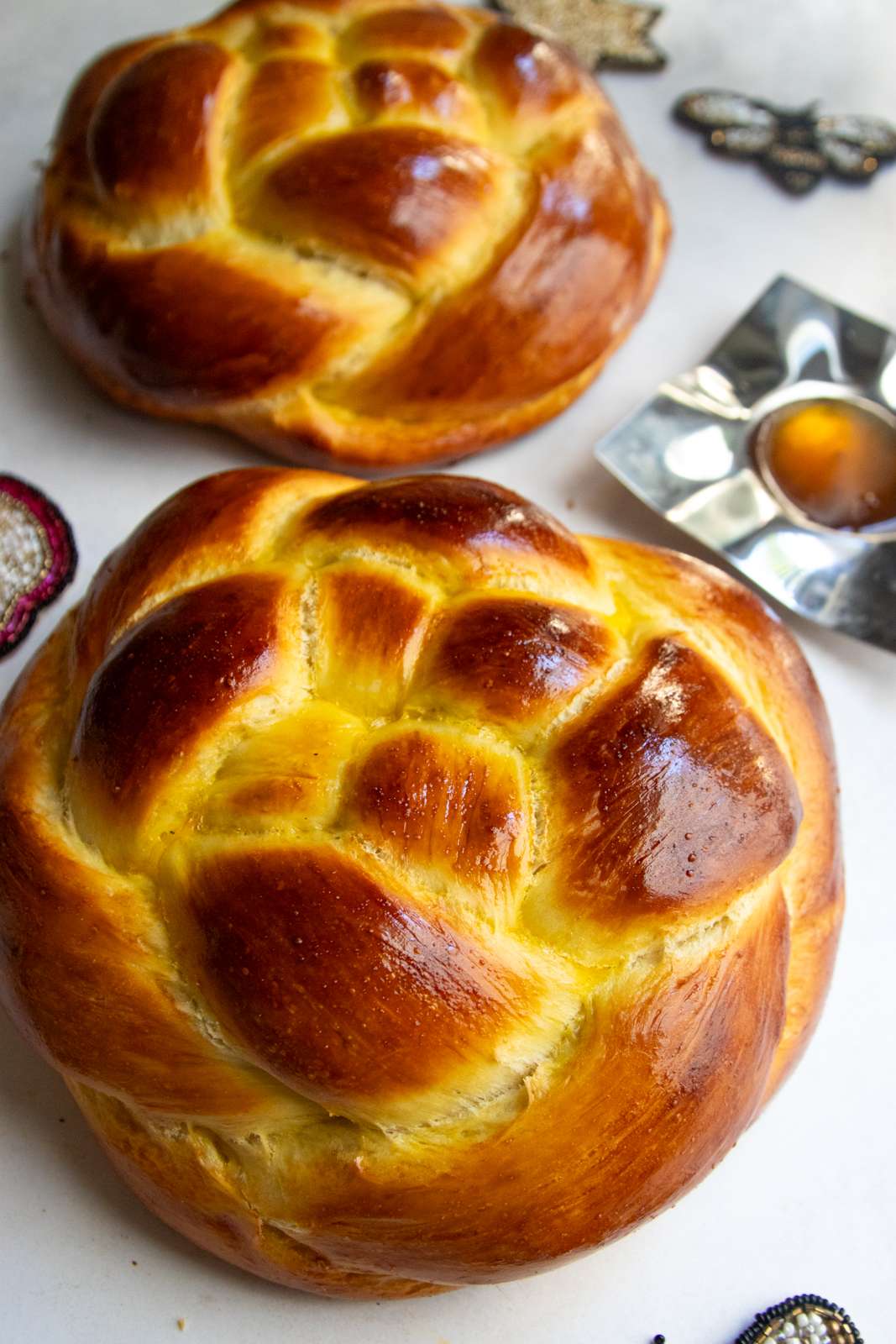Two round Rosh Hashanah challah loaves from above with honey and apples
